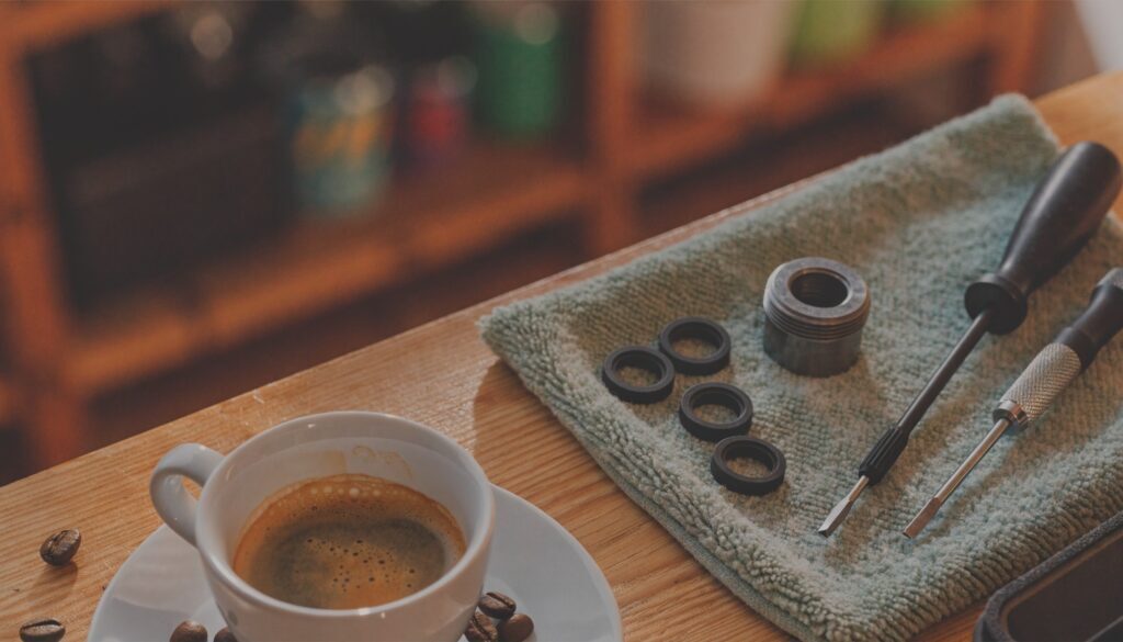 JURA Kaffeemaschine Reparatur: Dichtungen, Ventilteil und Schraubendreher auf einem Tuch neben einer Tasse Espresso
